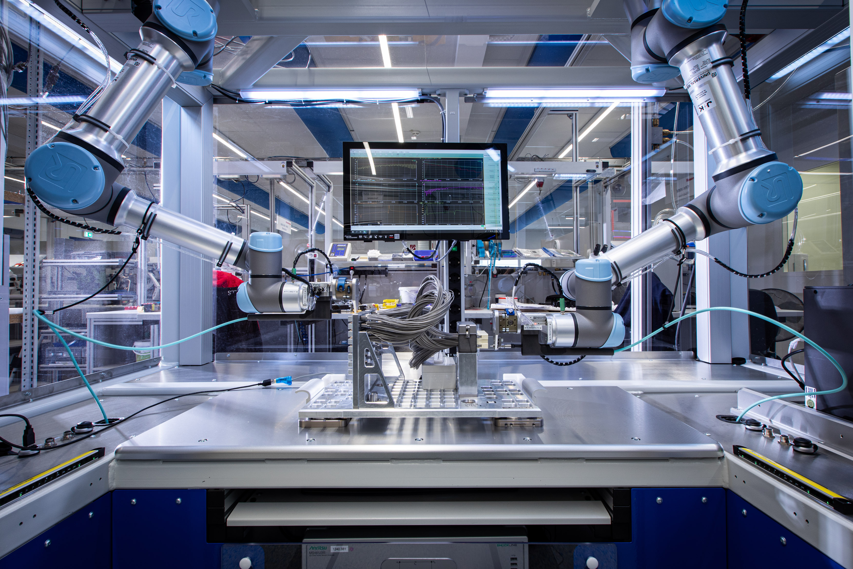 Prüfstand mit Roboterarmen und großem Monitor
